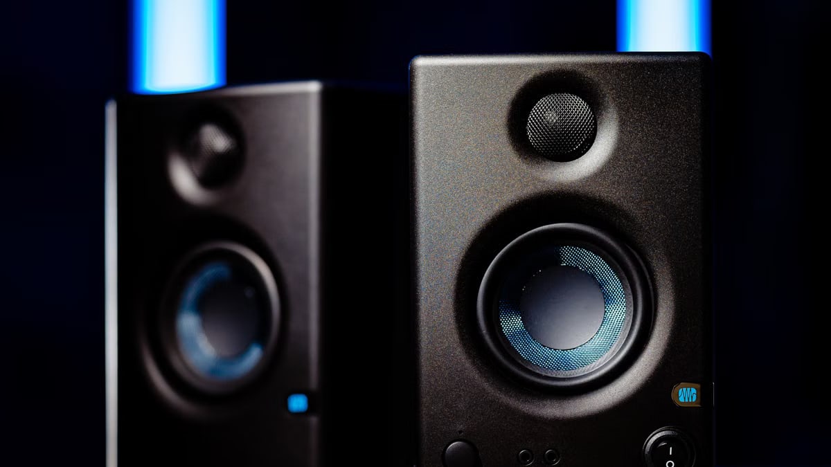 Close-up of modern black loudspeakers with blue accents in a studio setting.